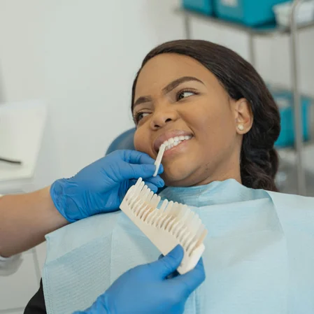 A patient smiling while a dental professional chooses the correct color for teeth whitening